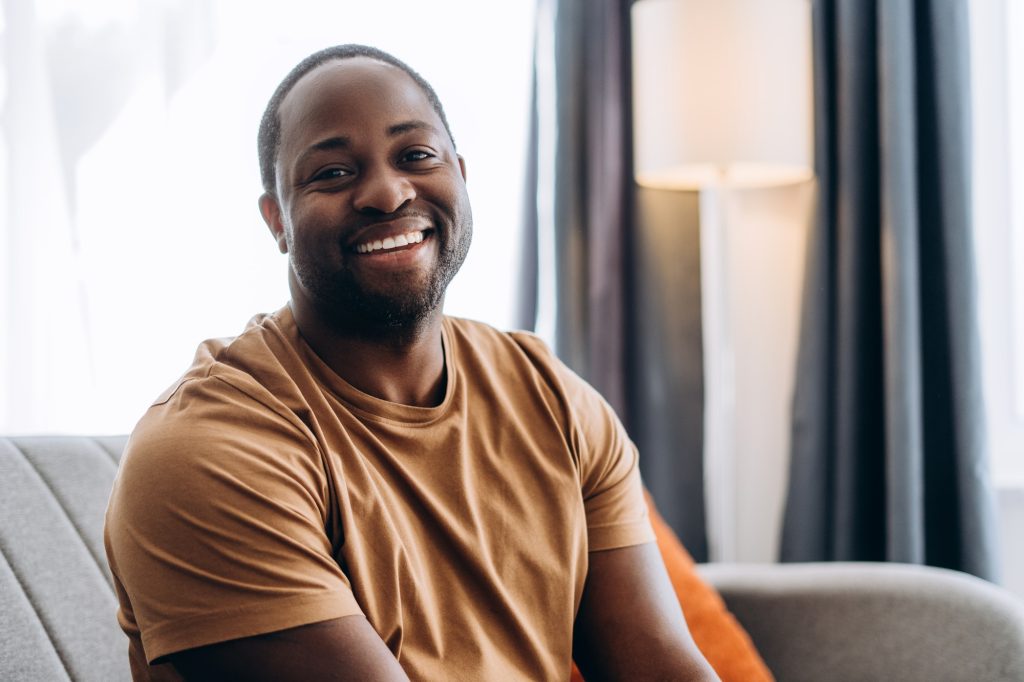 Happy handsome African American guy looking at camera at home